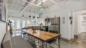 A modern kitchen with white cabinets, stainless steel appliances, and a wooden dining table.