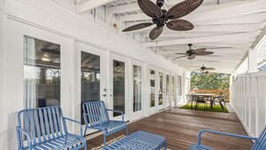 A covered outdoor area with blue metal chairs, a wooden deck, and ceiling fans.