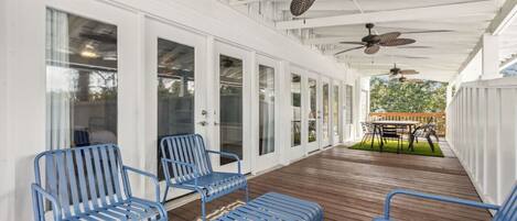 A covered outdoor area with blue metal chairs, a wooden deck, and ceiling fans.