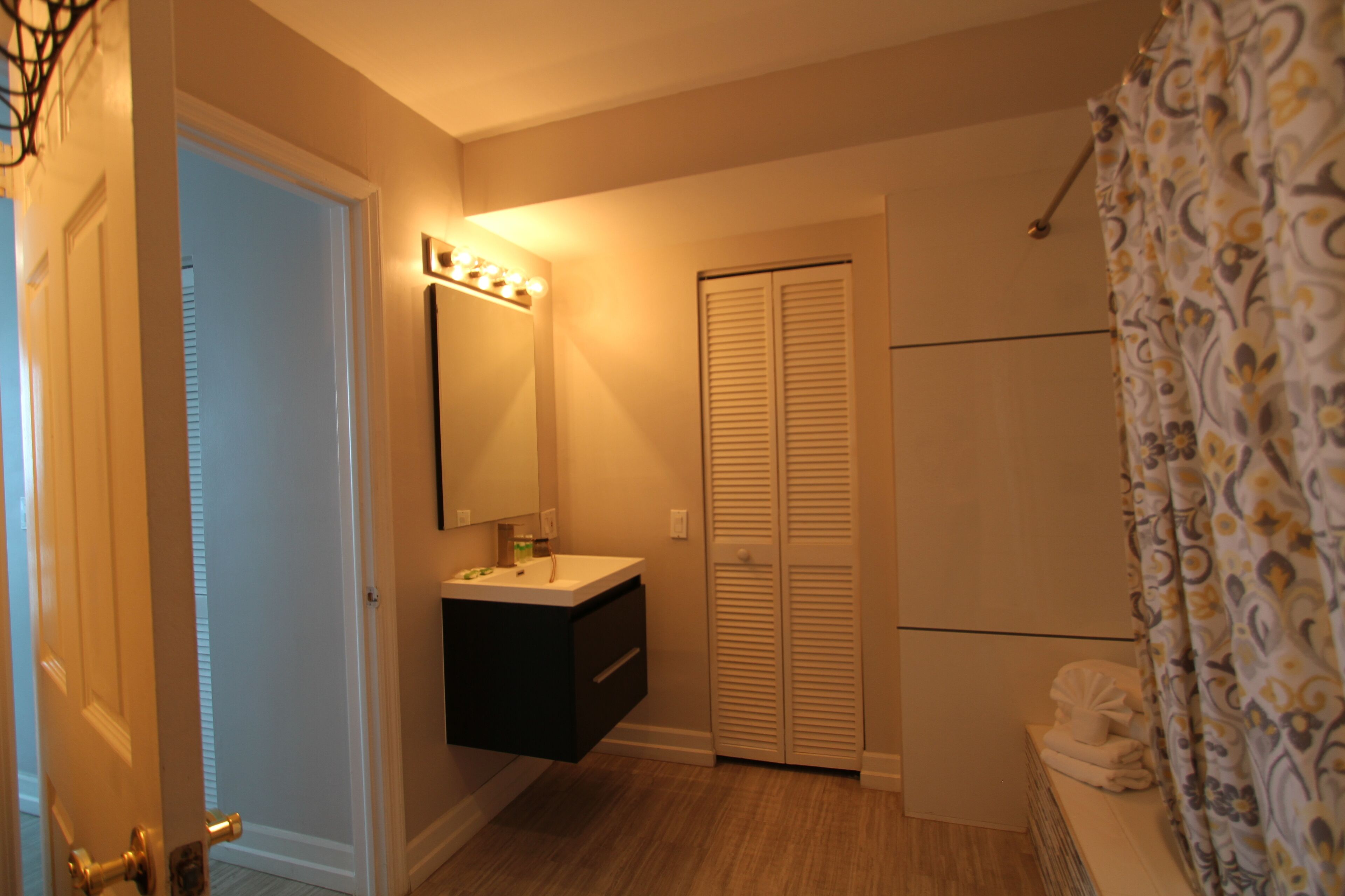 Une salle de bain avec un meuble-lavabo, un miroir et un dressing.
