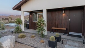 Una casa moderna con piscina, mobiliario de exterior y cactus.