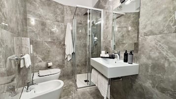 A modern bathroom with a glass-enclosed shower, a freestanding bathtub, and a vanity with a mirror.
