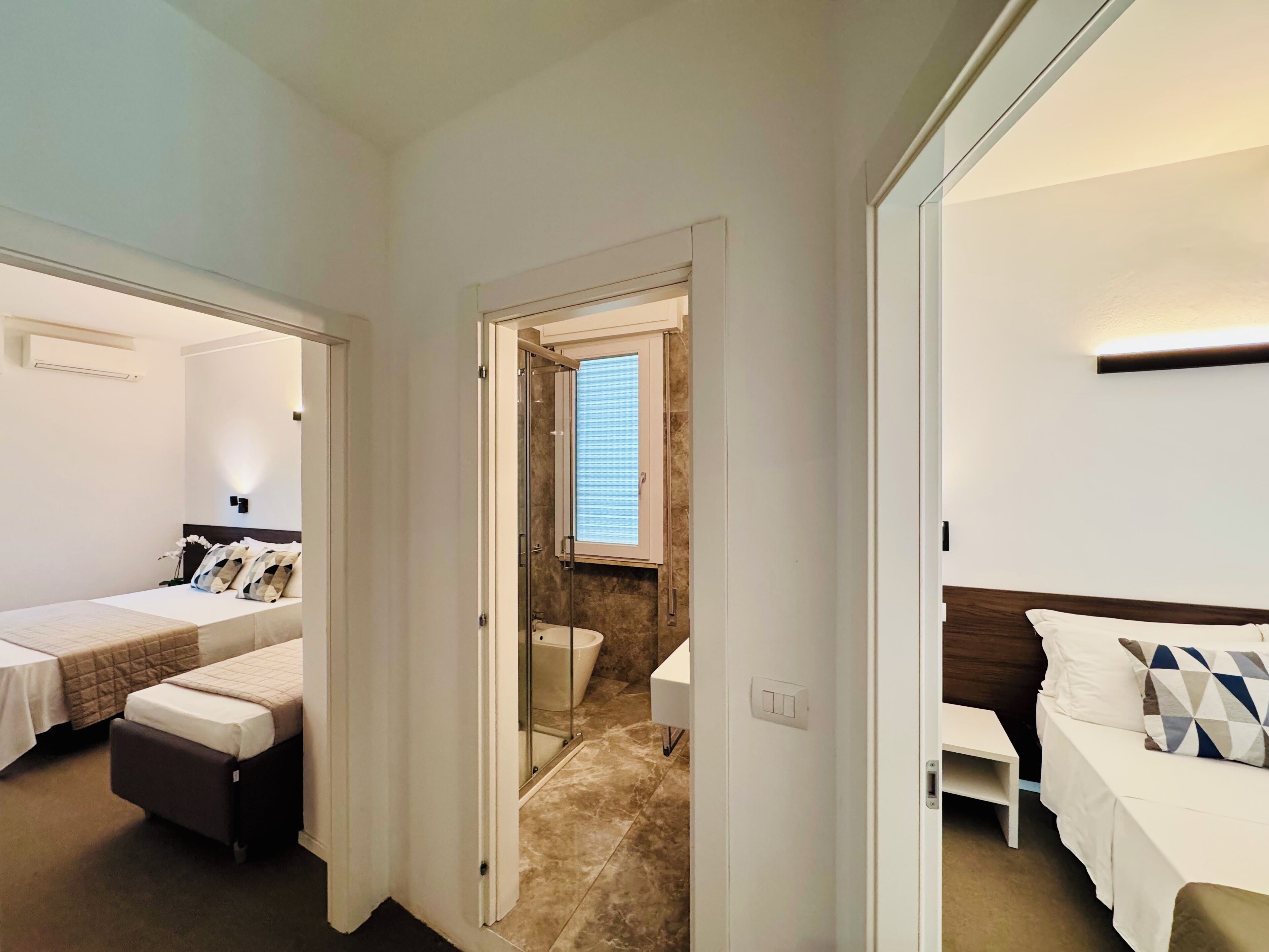 Et hotelværelse med seng, et lille bord, bruseområde og badeværelse.