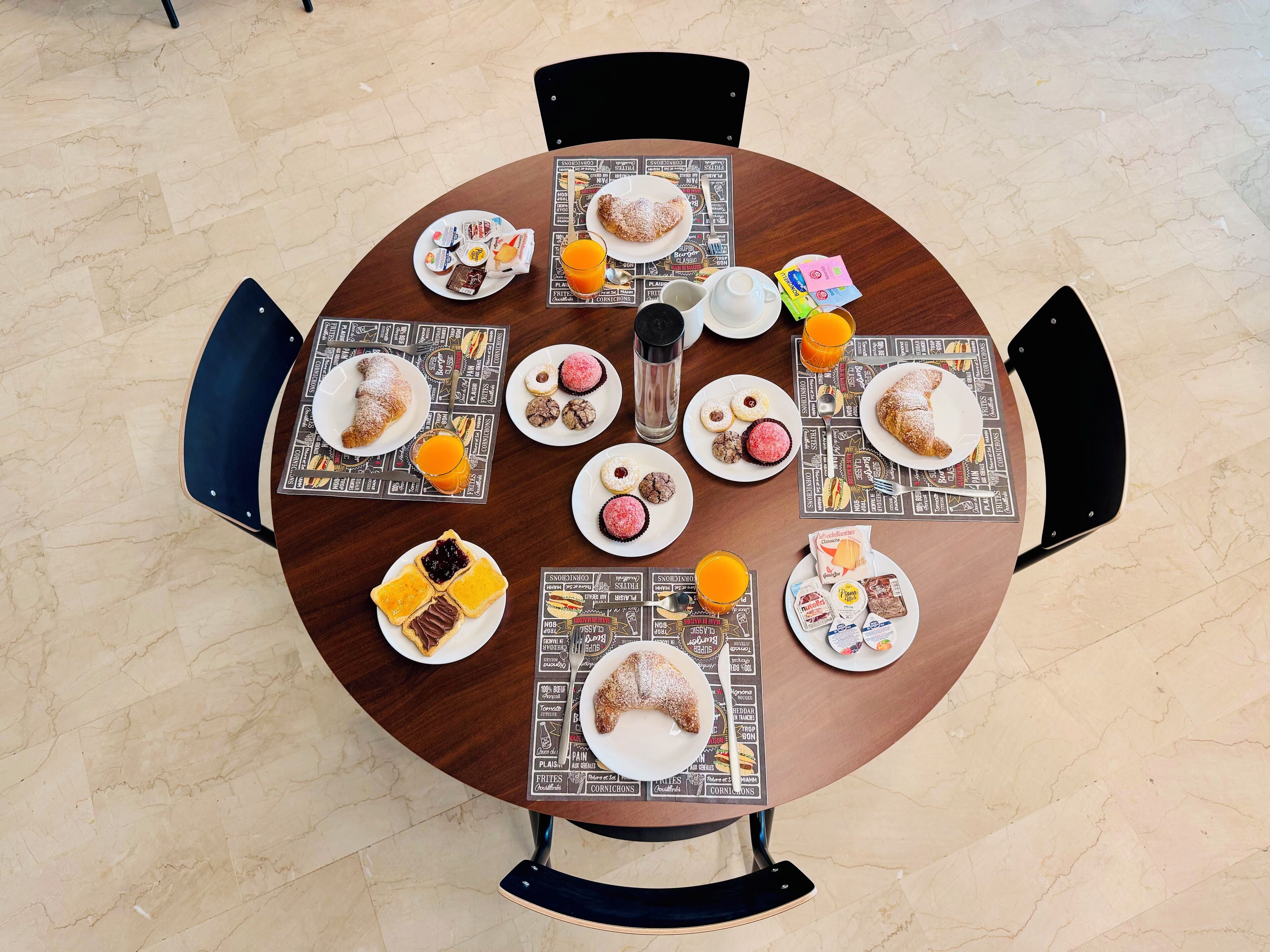 A round table with a placemat featuring various food items and a glass of orange juice.
