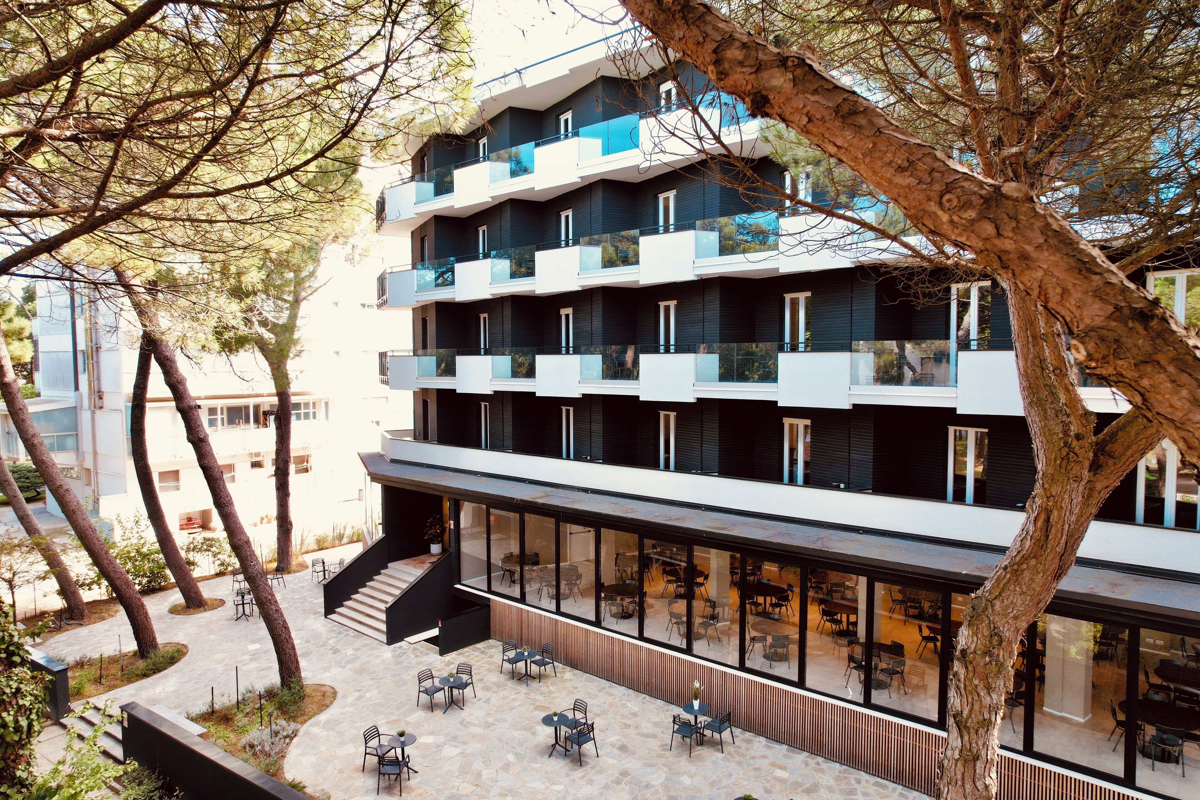 Un edificio moderno con varios balcones, mobiliario exterior y una escalera que lleva a un nivel superior.
