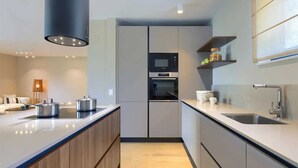 Une cuisine moderne dotée d’un îlot central, d’un four encastré et d’un four à micro-ondes.