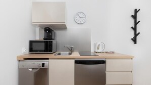 Une cuisine compacte équipée d’un four à micro-ondes, d’une machine à café, d’un évier et d’un lave-vaisselle.
