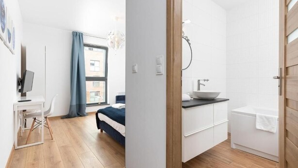 Une chambre à coucher moderne avec un lit, un bureau et une fenêtre avec des rideaux.