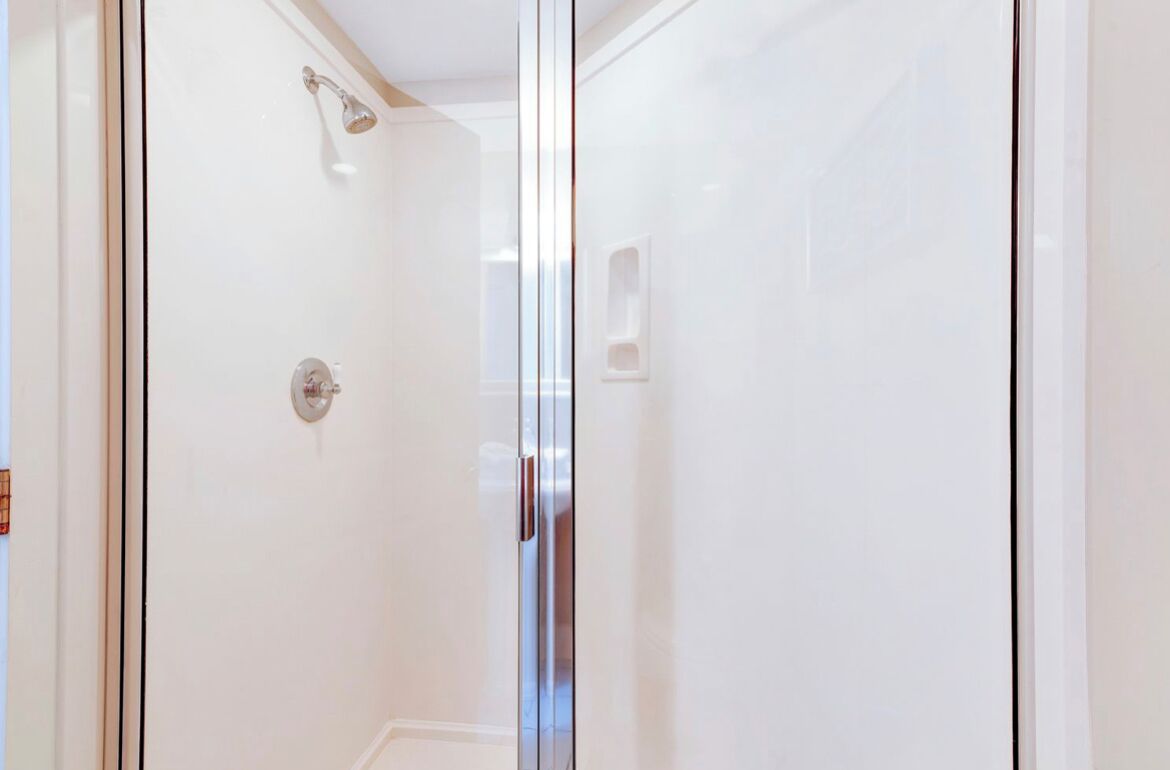 Une salle de douche fermée par des parois de verre, équipée d’un pommeau de douche et d’un panneau de commande.