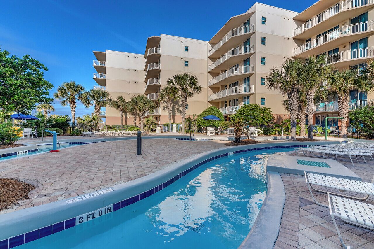 A swimming pool area with a 3 ft. deep end, surrounded by palm trees and lounge chairs.