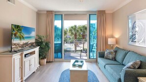 Une chambre d’hôtel avec un balcon, une télévision, un canapé et une table basse.