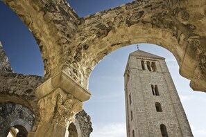 Um arco de pedra emoldura uma torre alta e estreita com janelas em arco.