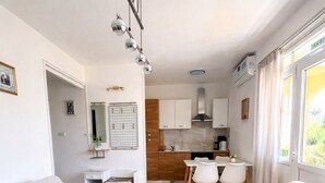 A modern living room with two sofas, a round coffee table, a dining table, and a kitchen in the background. - Seafront Paradise at Rab Island - Emily 3 (Kampor)