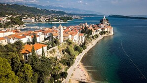 An aerial view of a coastal town with historic buildings, a prominent church, and a beach. - Seafront Paradise at Rab Island - Emily 3 (Kampor)