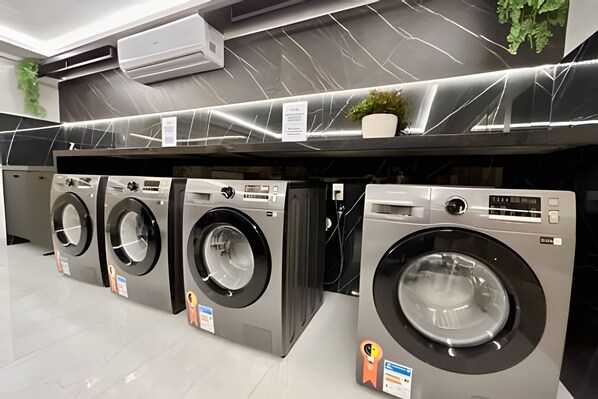 A row of front-loading washing machines in a commercial setting. - Unity Cabo Branco (João Pessoa)
