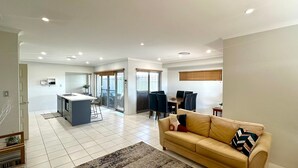A spacious living area with a sofa, a dining table, and a kitchen area with a central island.