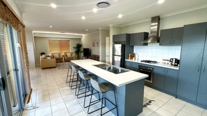A modern kitchen with a central island, bar stools, a built-in oven, and a stainless steel refrigerator.