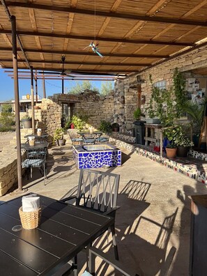 An outdoor patio with stone walls, a mosaic-tiled table, and metal chairs. - Sunsets. Stars. Serenity. Organic Eco-Dome in Terlingua. (Terlingua)