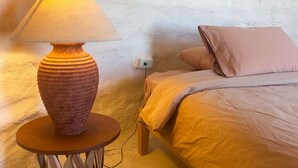 Una cama con estructura de madera y una mesa redonda con una lámpara a su lado.