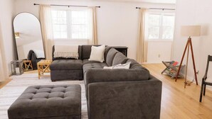 A modern living room with a sectional sofa, a small table, a large mirror, and a floor lamp. - Private Home Near I71, Snow Trails, Golf & Race Tracks (Mansfield)