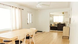 A spacious room with a wooden dining table and chairs, a small kitchenette, and a door leading to another room. - Private Home Near I71, Snow Trails, Golf & Race Tracks (Mansfield)