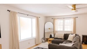 A modern living room with a large sectional sofa, a small table, and a ceiling fan. - Private Home Near I71, Snow Trails, Golf & Race Tracks (Mansfield)