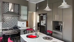 A modern kitchen with a central island, stainless steel appliances, and grey cabinetry.