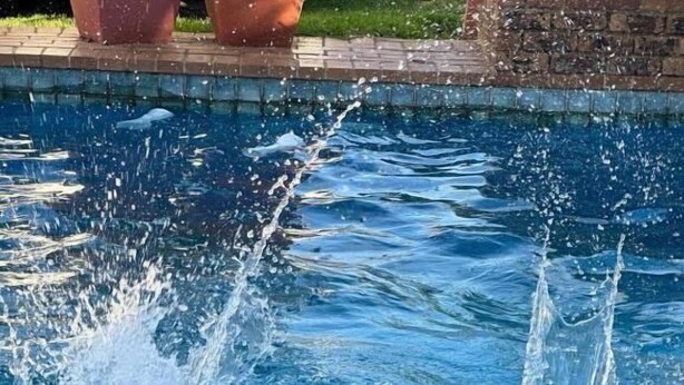 A person in a swimming pool with water splashing around them.