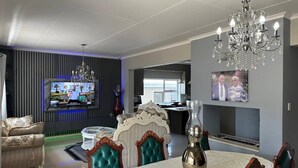 A modern living room with a TV, dining table, and chairs.