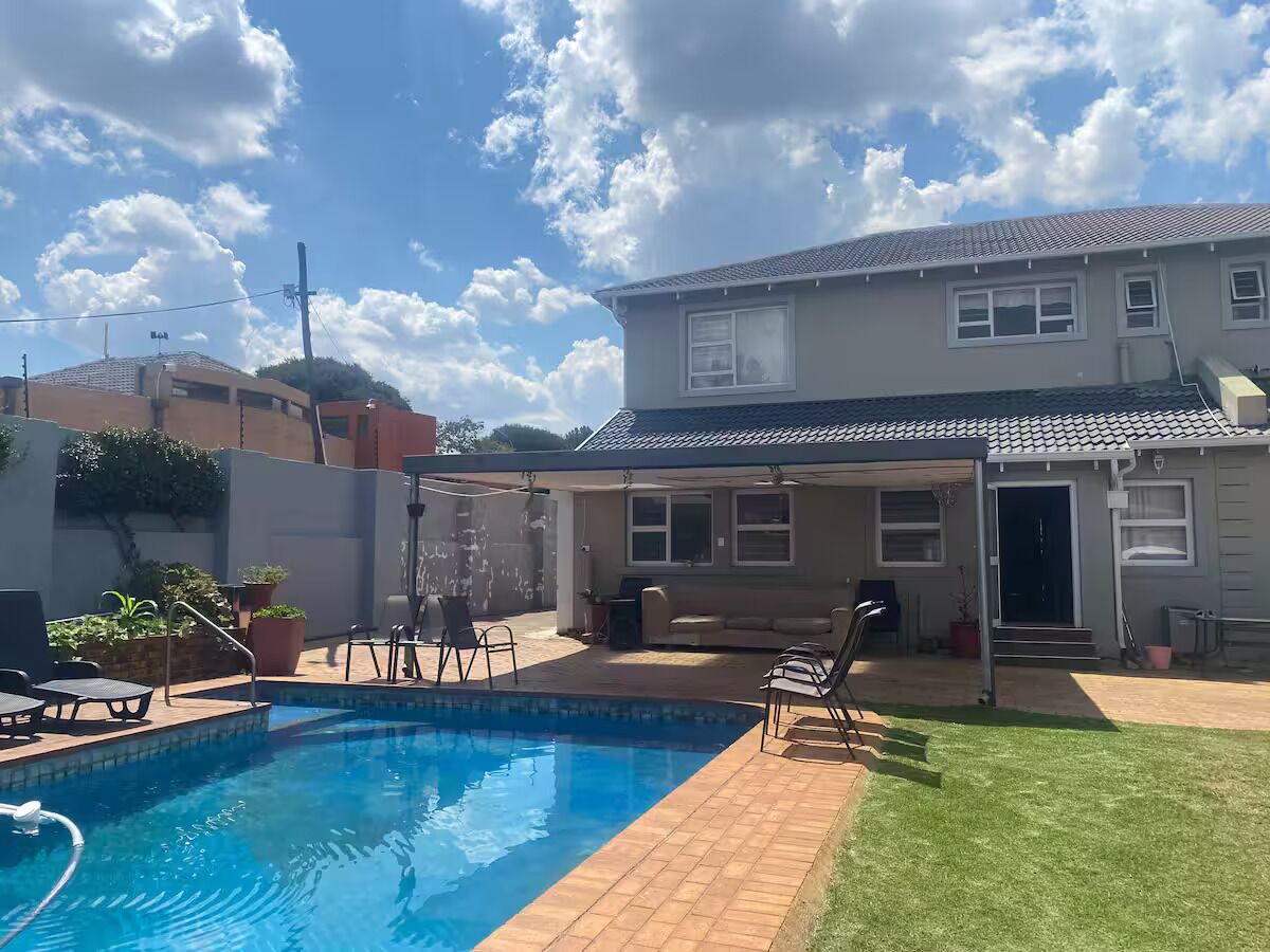 Un jardin avec une piscine, un patio couvert et une maison.