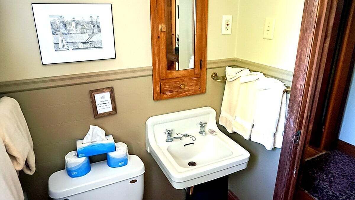 Un baño con inodoro, lavabo, espejo, un cuadro enmarco y toallas.