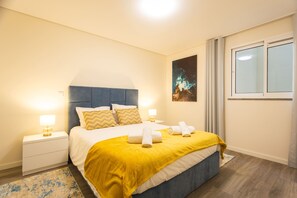 Ein Schlafzimmer mit einem Bett, Nachttischen, einem Fenster und einem Bild an der Wand.