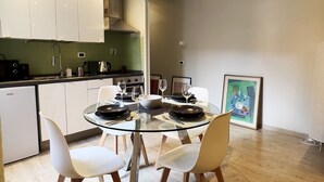 Eine moderne Küche mit weißen Schränken, einem Glastisch und Holzsesseln.