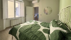 Ein Schlafzimmer mit einem Bett, einem Fenster, einer Klimaanlage und einer Tür zu einem anderen Raum.