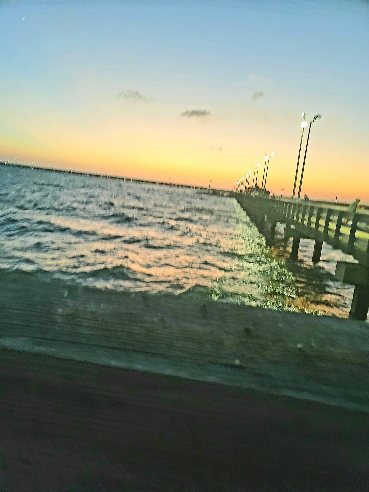 A pier extending into calm waters with a clear sky.