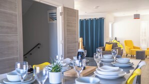 A dining area with a table set for six, a sofa, and a chair in the background. - Wight Stone Luxury Townhouse - Breathtaking Views  (Sandown)