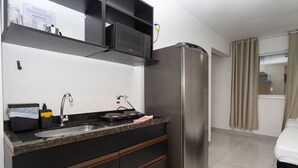 Een kleine keuken met een roestvrijstalen koelkast, een magnetron, een spoelbak en een aanrecht met een broodrooster.