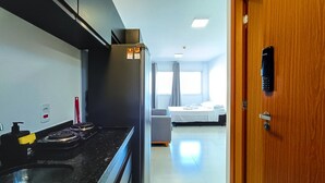 A modern kitchen with a stove, refrigerator, and a wooden door with a keypad lock.