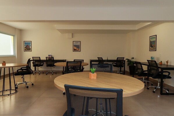 A conference room with a round table, black chairs, and framed pictures on the walls.
