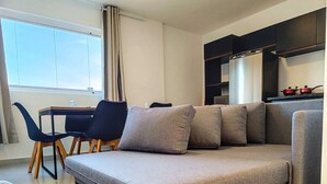 A modern living room with a sofa, a dining table, and chairs.