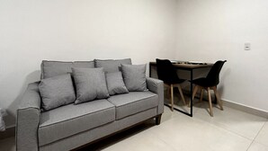 A room with a grey sofa, two black chairs, and a wooden table. - Studio 603 - proximo ao metro Santana - SP (São Paulo)