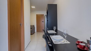 A narrow hallway with a dining area featuring a black table set with plates, glasses, and red cups. - Studio 615 - Santana - 8 min de carro do Anhembi (São Paulo)