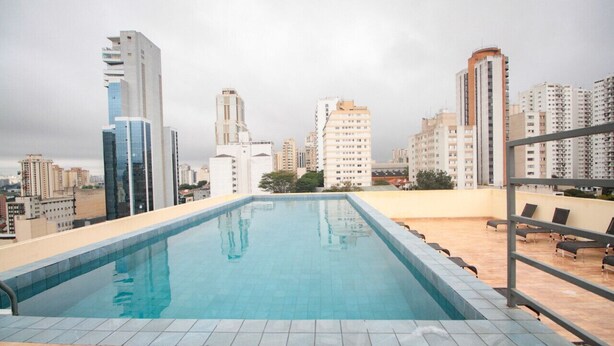 A rooftop swimming pool with a cityscape view, surrounded by high-rise buildings. - Studio 615 - Santana - 8 min de carro do Anhembi (São Paulo)