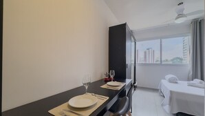 A modern hotel room with a dining area, a bed, and a large window offering a city view. - Studio 615 - Santana - 8 min de carro do Anhembi (São Paulo)