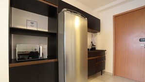 A modern kitchen with a built-in refrigerator, a microwave, and a coffee maker on a wooden countertop. - Studio 604 - Santana - proximo ao metro Santana (São Paulo)