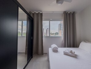 A hotel room with a bed, a wardrobe, a window with curtains, and a view of buildings. - Studio 611 - Santana - 8min do Expo Center Norte (São Paulo)