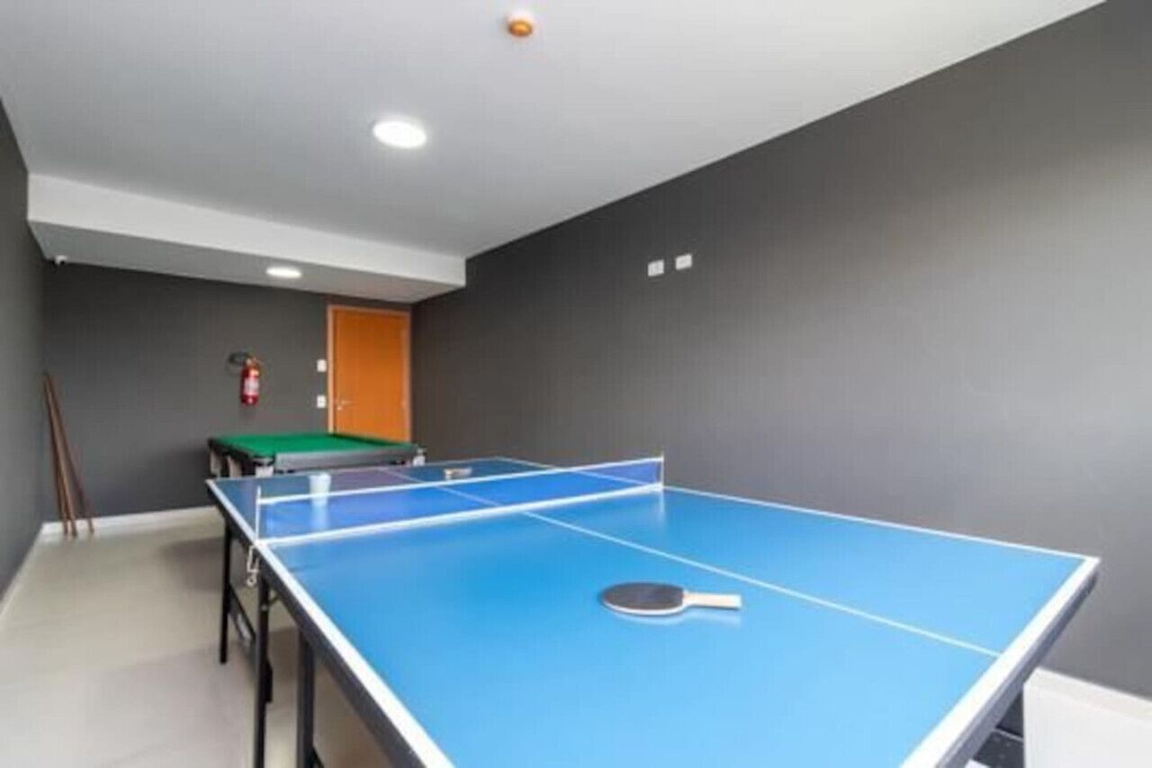 Una habitación con una mesa de ping pong, un extintor y una puerta.