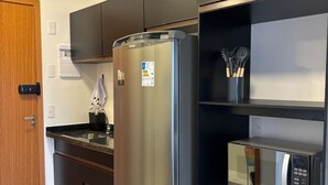 A modern kitchen with a stainless steel refrigerator, a microwave, and a wooden door.