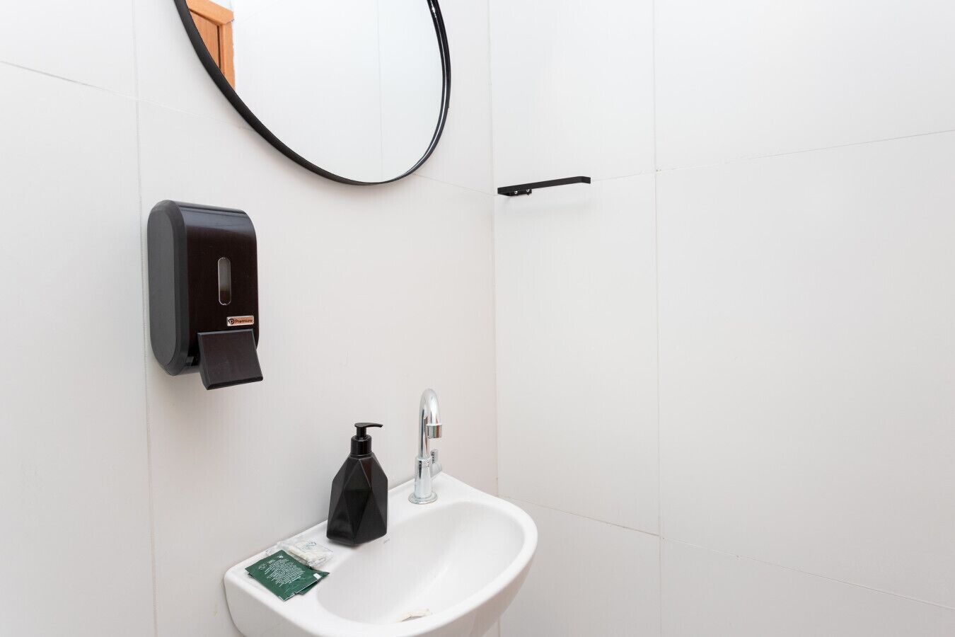 Eine Toilette mit einem weißen Waschbecken, einem Seifenspender und einem an der Wand montierten Händetrockner.