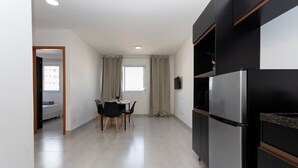 A modern kitchen with a built-in refrigerator, a dining area with a table and chairs, and a window with curtains.